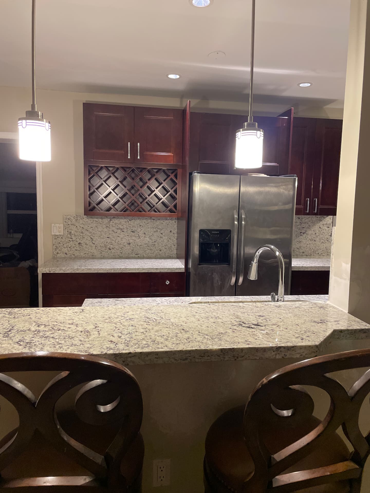 Completed granite bar peninsula with pendant lights and built-in wine rack beyond