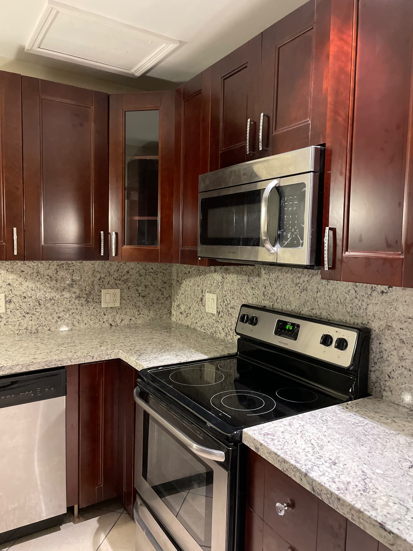 Completed corner cabinetry with glass-front door, granite backsplash and stainless range