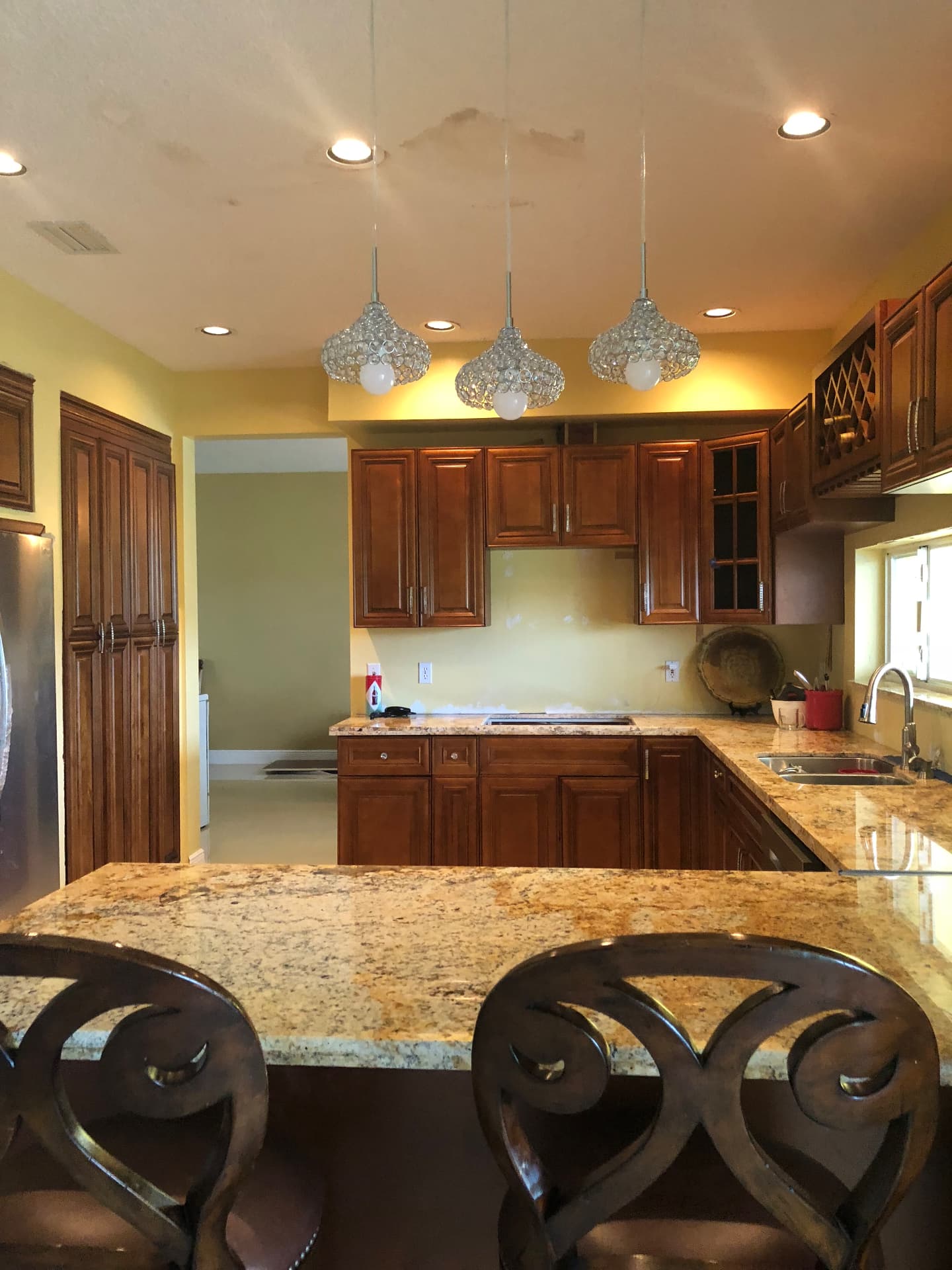 Completed Cooper City kitchen with granite peninsula, crystal pendants and custom wood cabinetry