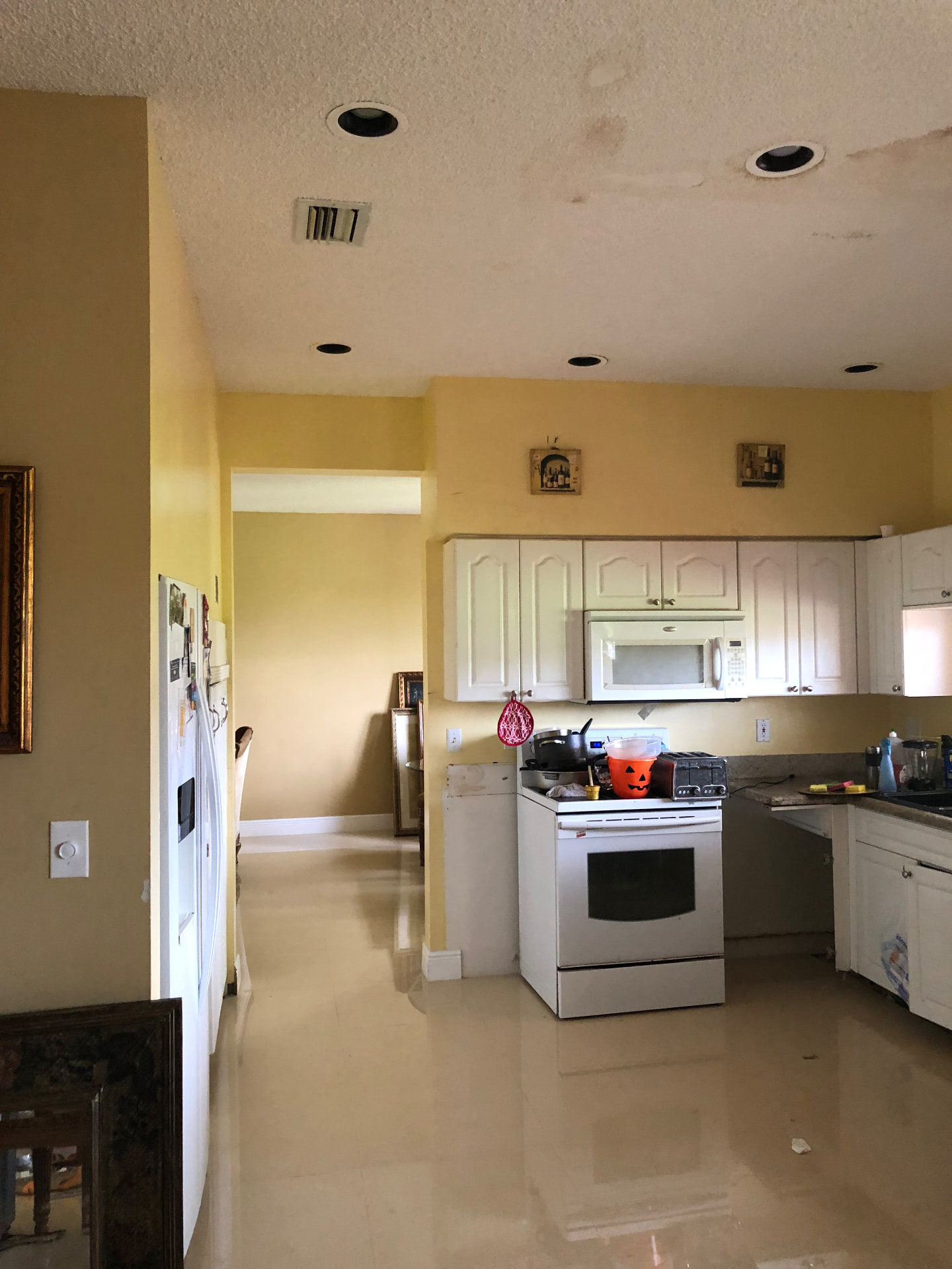 Existing Cooper City kitchen before remodeling with yellow walls and dated white cabinetry