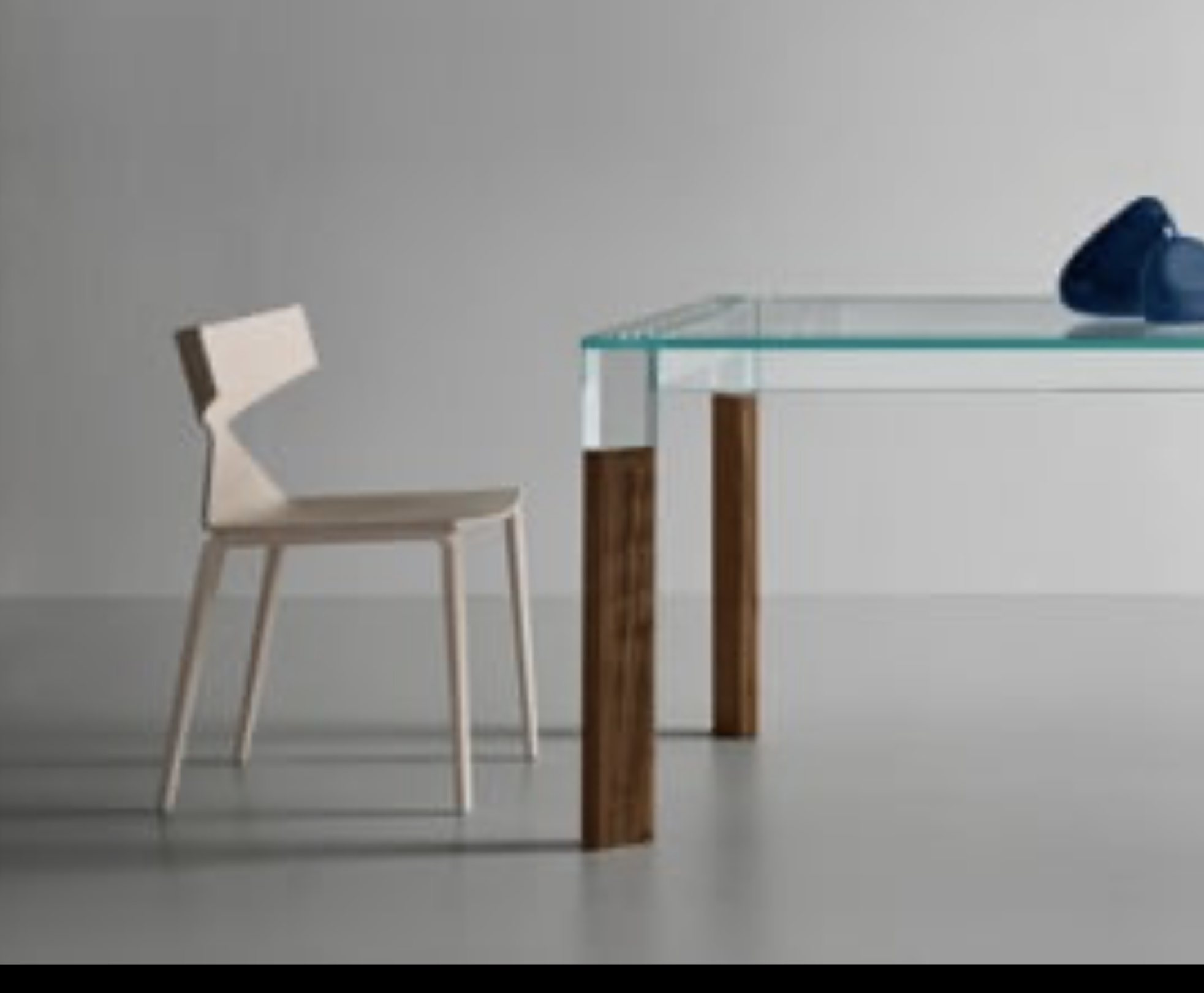 Minimalist glass dining table with solid wood legs and a modern chair